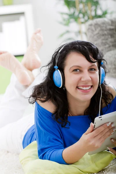 Jovem com tablet e fones de ouvido em casa — Fotografia de Stock