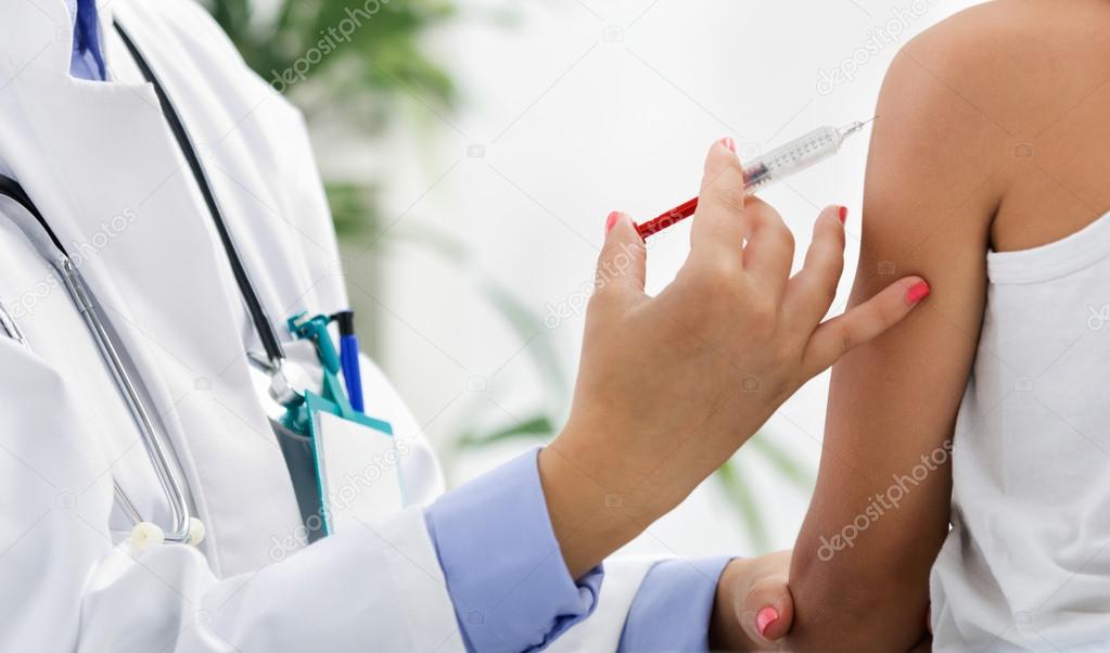 Female doctor making injection to little boy