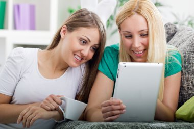 twee gelukkige jonge vrouwen met digitale tablet