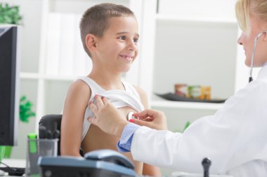 Kadın doktor mutlu çocuğu muayene ediyor, gülümsüyor..