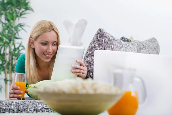 Bella ragazza moderna sdraiata sul divano con tablet elettronico — Foto Stock