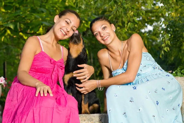 Dos hermosa joven jugando con el cachorro en el parque — Foto de Stock