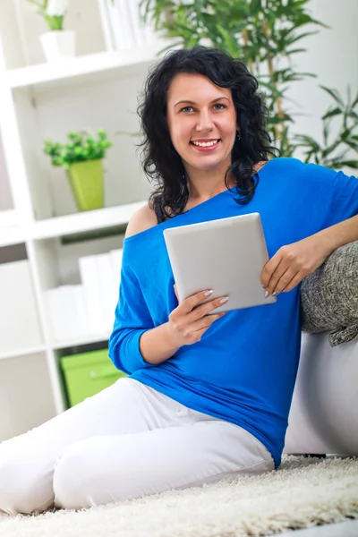 Schöne Frau lacht und hält ein digitales Tablet in der Hand — Stockfoto