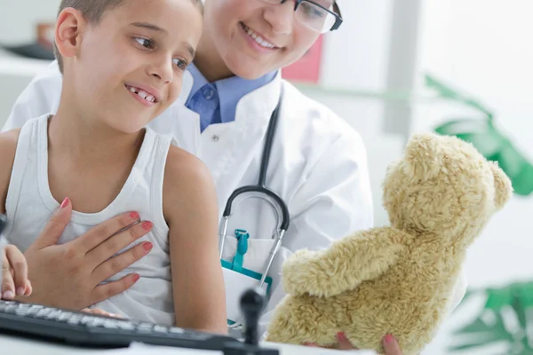 Docteur calme un jeune garçon au bureau — Photo