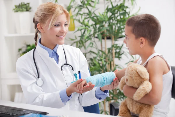 Arzt untersucht, kleiner Junge mit blauem Gips — Stockfoto