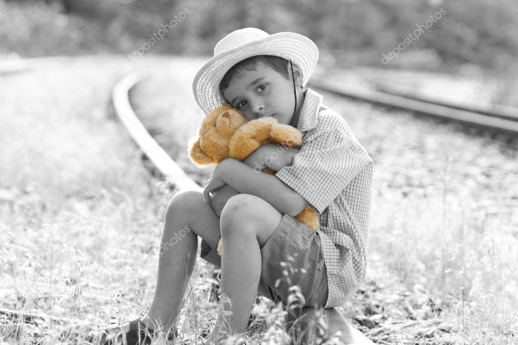 runaway child on railroad hugging his teddy bear
