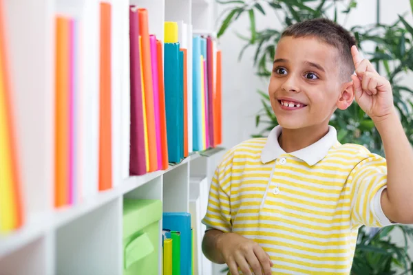 Menino alegre estudante tem ideia na biblioteca — Fotografia de Stock