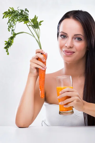 Mujer joven sosteniendo jugo de zanahoria y zanahoria — Foto de Stock