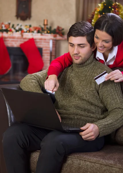 Пара, использующая кредитную карту в интернет-магазине в рождественский вечер — стоковое фото