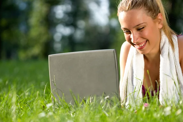 Femme après l'exercice dans le parc au repos et en utilisant un ordinateur portable — Photo