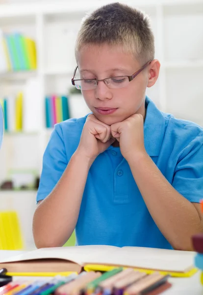 Ung pojke med glasögon lär sig från böcker — Stockfoto