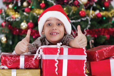 küçük çocuk Noel ağacının yanında hediye kutusu ile gülümseyen