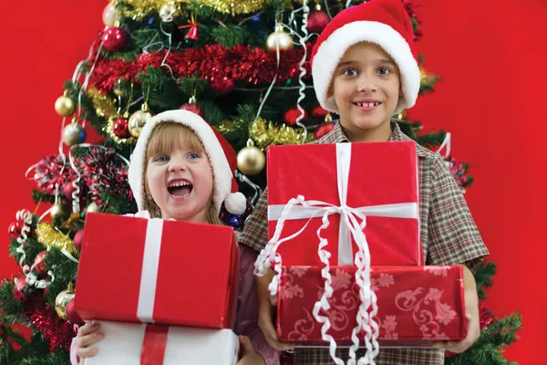 Frère et sœur tiennent des cadeaux en main le soir de Noël — Photo