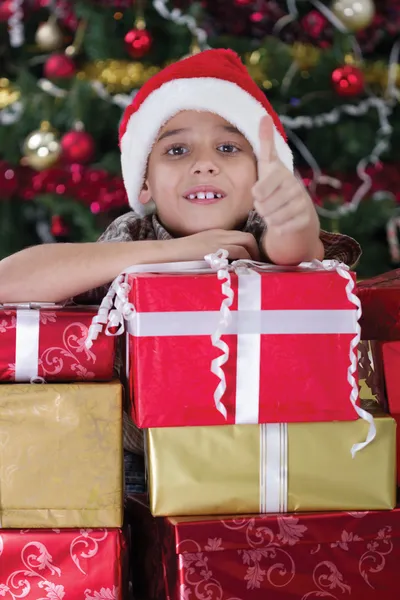 Ευτυχής μικρό αγόρι χαμογελά με κουτί δώρου δίπλα το χριστουγεννιάτικο δέντρο — Φωτογραφία Αρχείου