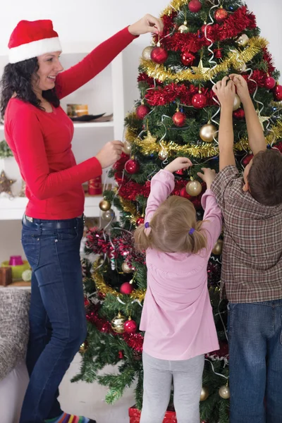 Ragazza e ragazzo aiutando la madre a decorare l'albero di Natale — Foto Stock