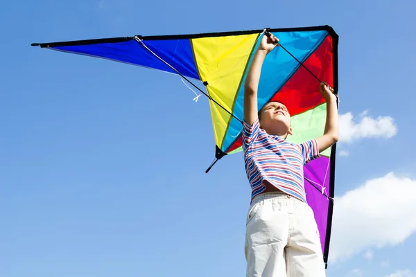 Glücklicher kleiner Junge lässt einen Drachen in den blauen Himmel steigen — Stockfoto