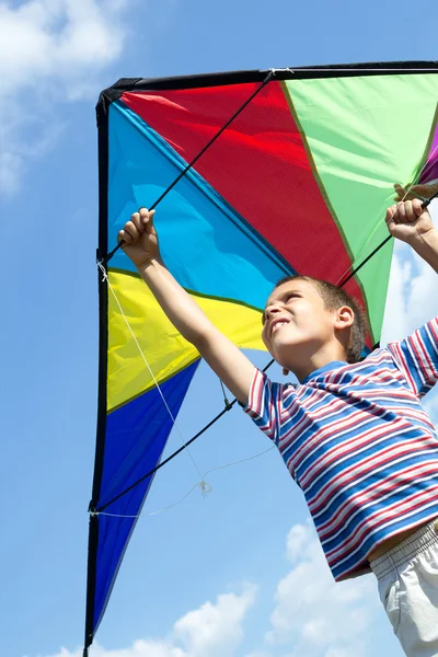 Kleine jongen vliegen een vlieger in de blauwe hemel — Stockfoto