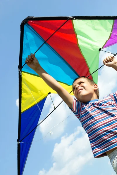 Kleine jongen vliegen een vlieger in de blauwe hemel — Stockfoto