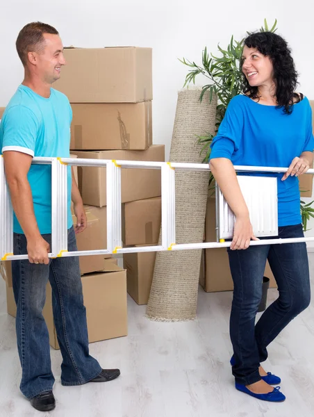 Young happy couple with a ladder in his hands in new home — Stock Photo, Image