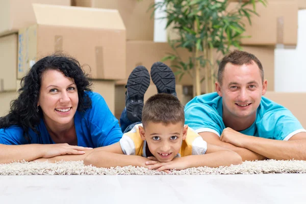 Счастливая пара с ребенком в их новом доме лежит на полу с — стоковое фото