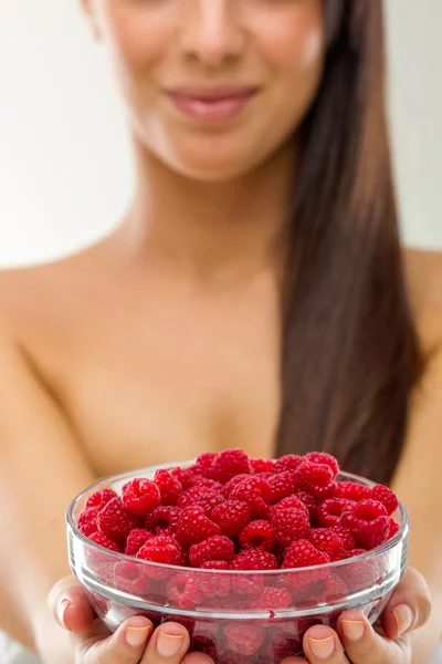 Beautiful woman holding a pot of raspberries — Stock Photo, Image