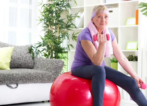 Glückliche Seniorin sitzt auf Gymnastikball und übt — Stockfoto