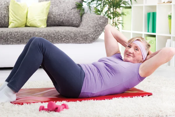 Senior woman doing curl-ups — Stock Photo, Image