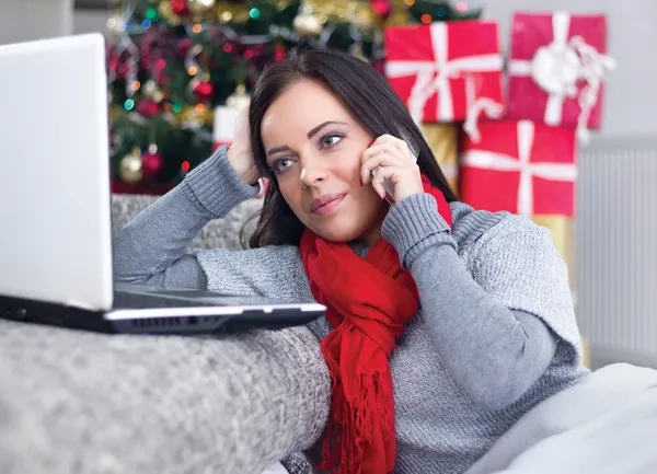 Giovane donna con computer portatile seduta vicino all'albero di Natale — Foto Stock