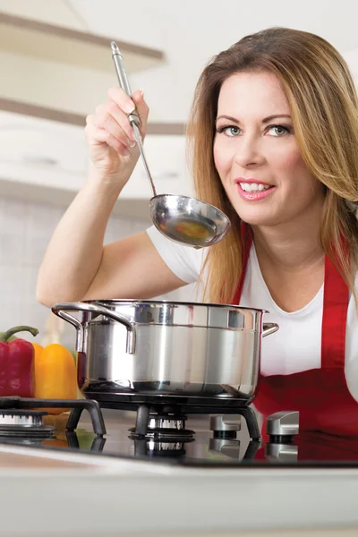 Schöne junge Frauen kochen und testen das Essen in der Küche — Stockfoto