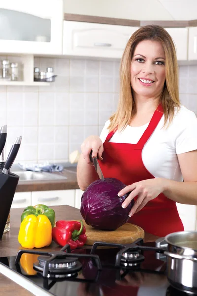 Junge moderne Hausfrau schneidet zu Hause Rotkohl — Stockfoto