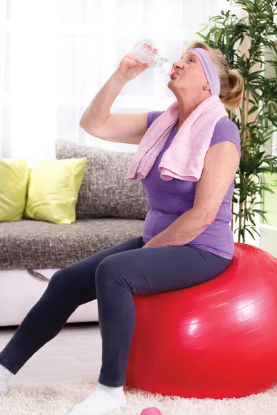 Mujer mayor bebiendo agua después de entrenar en casa — Foto de Stock