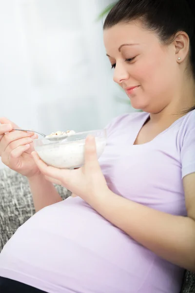 Sorridente bella donna incinta mangiare cereali — Foto Stock