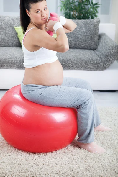 Беременная женщина делает упражнения мышцы бицепса с помощью гантели whil — стоковое фото
