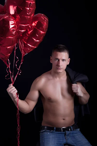 Svalnatý mladý muž drží balónek ve tvaru srdce — Stock fotografie