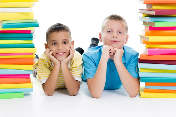 Studenten sitzen hinter einem Stapel Bücher auf weißem Hintergrund — Stockfoto