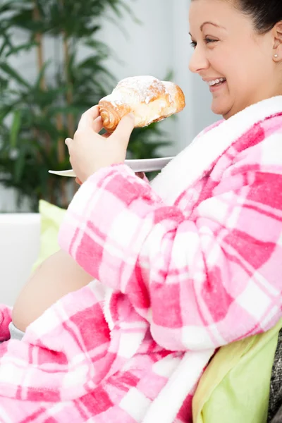 Junge lächelnde schwangere Frau frühstückt im Bett — Stockfoto