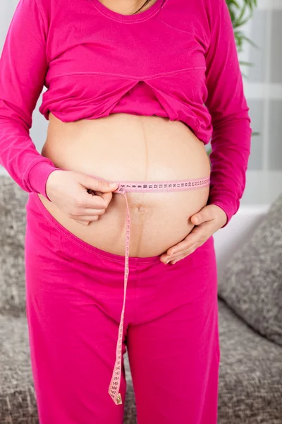 Pregnant woman measuring her growing — Stock Photo, Image