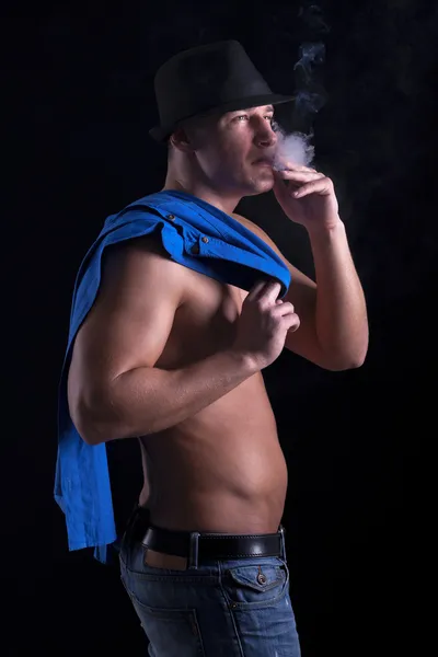 Мускулистый молодой человек, курящий сигарету — стоковое фото