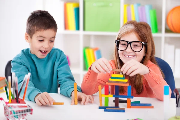 Sorrindo irmã mais velha brincando com o irmão mais novo com blo de madeira — Fotografia de Stock