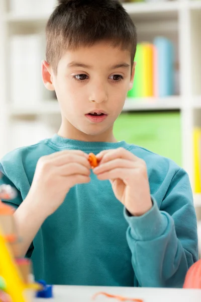 Cute little boy moulds from plasticine on table — Stock Photo, Image