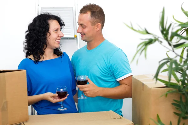 Happy couple celebrating moving to new house with red wine — Stock Photo, Image