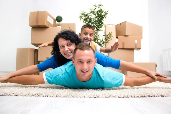 Paar mit Kind im neuen Zuhause, das mit Auto auf dem Boden liegt — Stockfoto