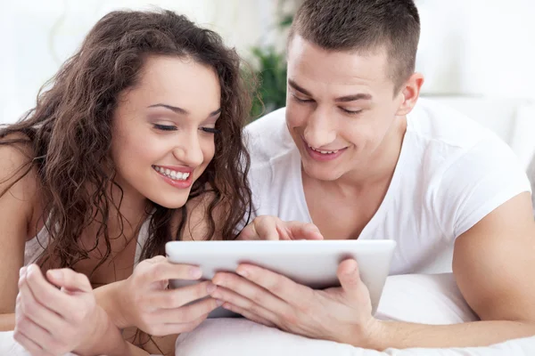 Young couple sitting on the bed using tablet pc — Stock Photo, Image