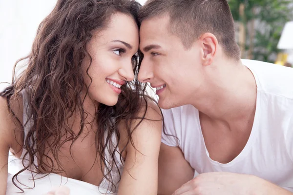 Joven hombre y mujeres enamorados acostados en la cama — Foto de Stock