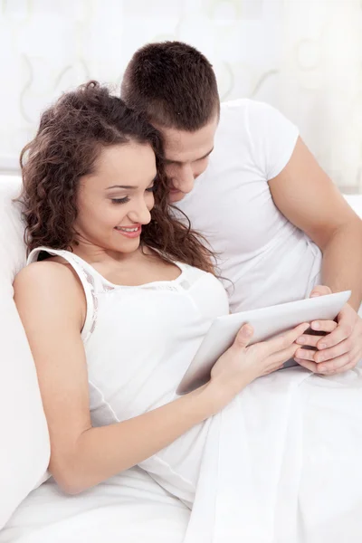 Jeune couple couché sur le lit en utilisant la tablette pc — Photo