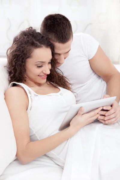 Young couple lying on the bed using tablet pc — Stock Photo, Image