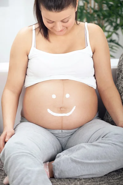 妊娠中の女性は彼女の腹に笑顔を描画します。 — ストック写真