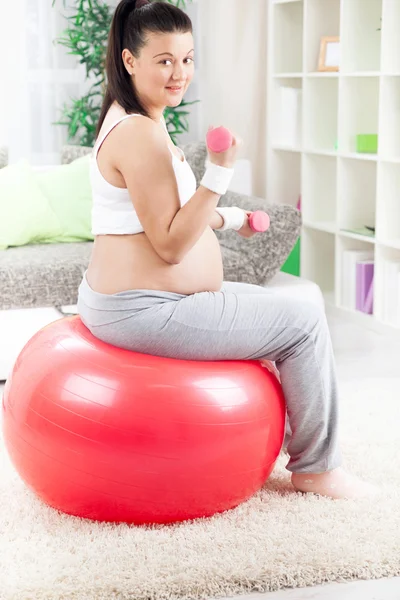 Беременная женщина делает упражнения мышцы бицепса с помощью гантели whil — стоковое фото