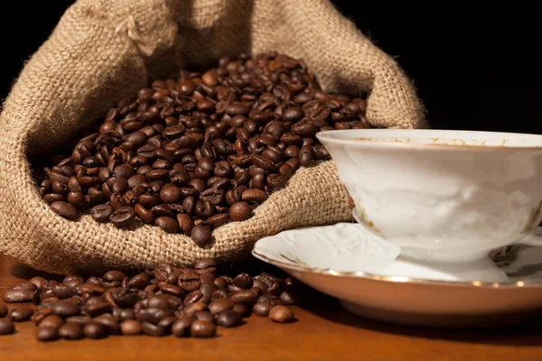 Koffie bonen in jute zak tegen donkere achtergrond — Stockfoto