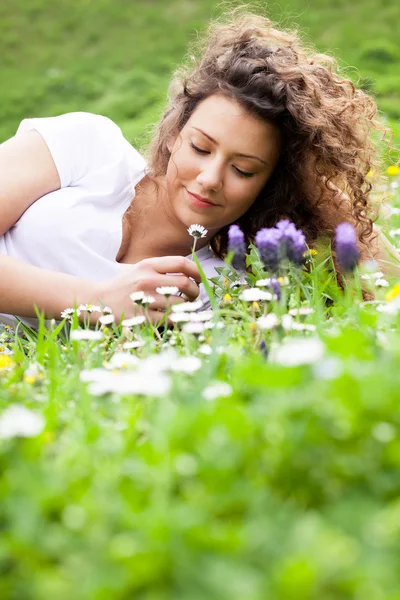 Menina bonita nova que coloca no campo de flores, conceito de verão — Fotografia de Stock